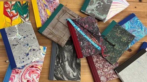 Colorful marbled notebooks scattered on wooden table.