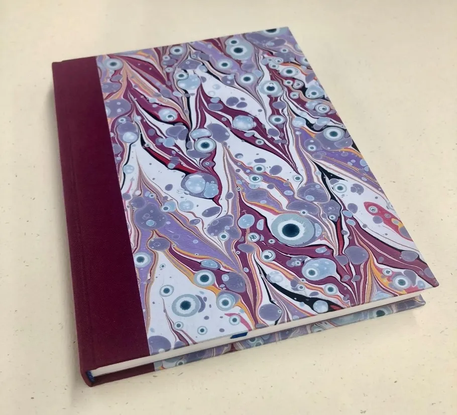 Colorful marbled notebook on beige surface.