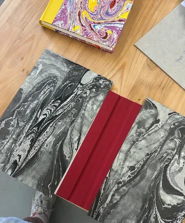 Marmorierte Bücher und Papier auf Holztisch.