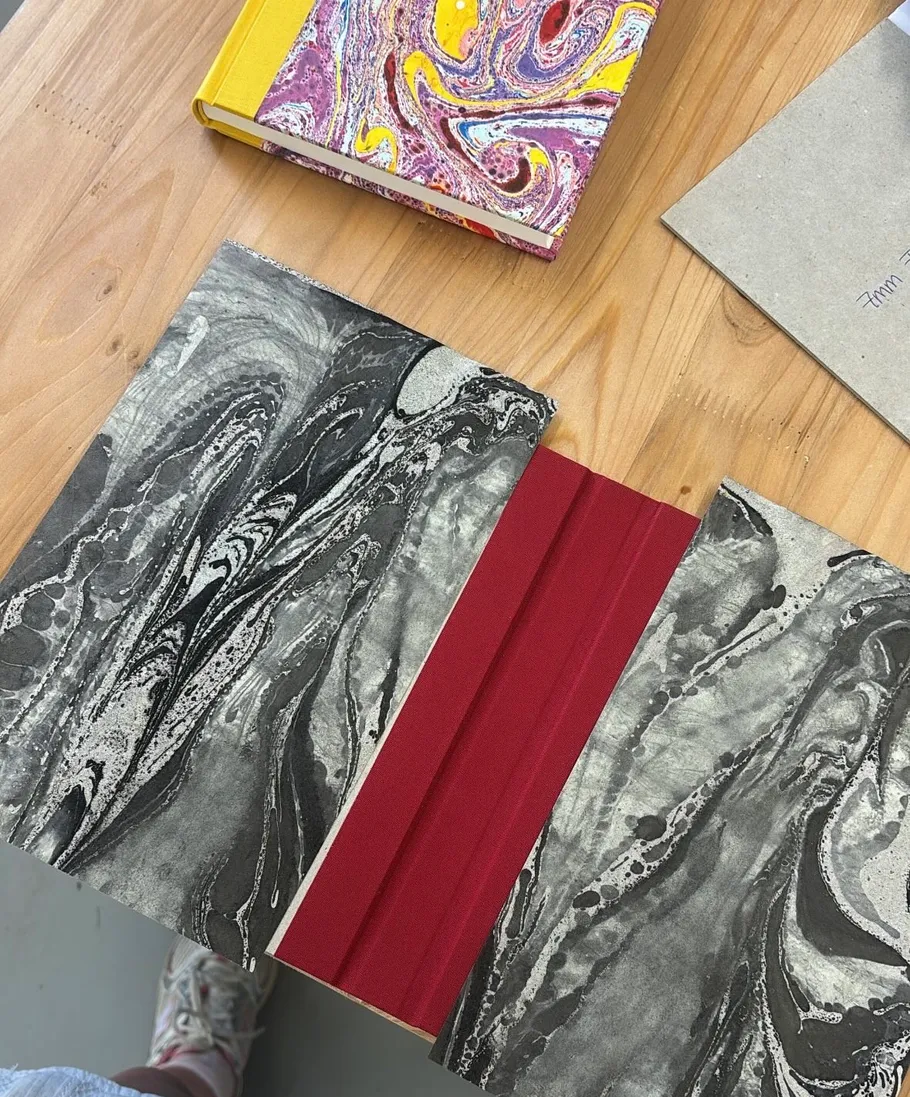 Marmorierte Bücher und Papier auf Holztisch.