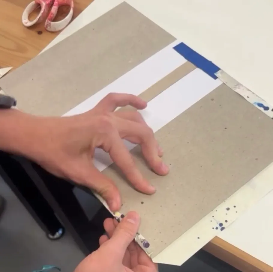 Hände falten Papier auf einem Tisch.