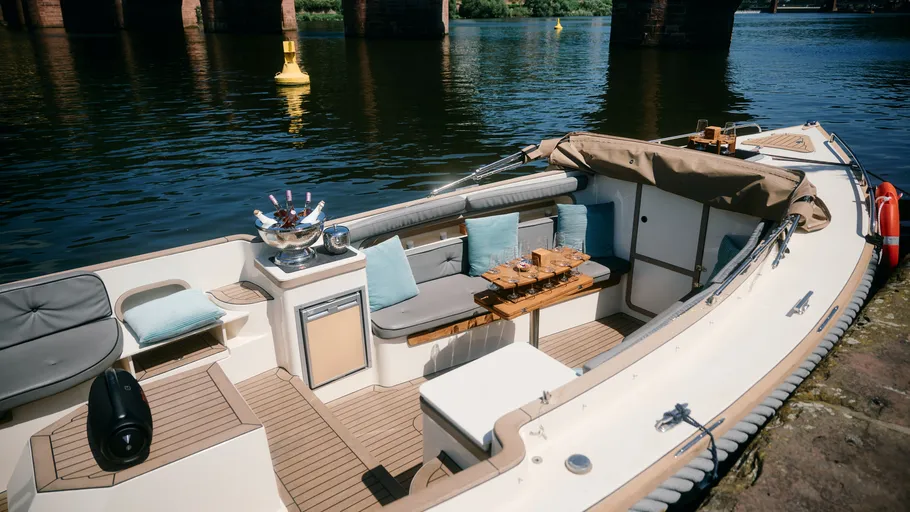 Boat moored by riverside with seating area.