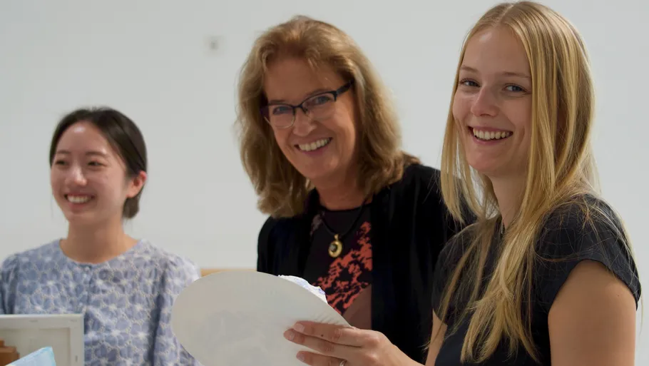 Three women smiling indoors with papers.