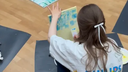 Person painting on canvas in an art class.