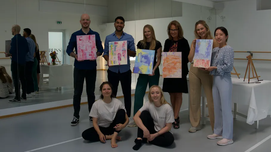 Group of people holding paintings in studio.