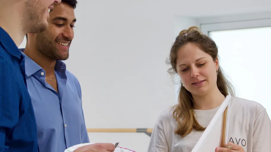 Three people discussing in a bright room.