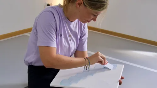 Woman applying paint on canvas in studio.