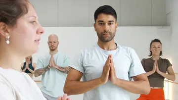Gruppe praktiziert Yoga drinnen.