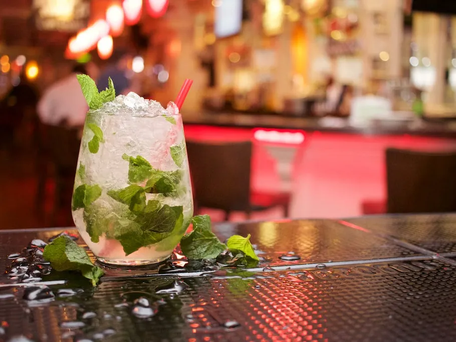 A cocktail glass with mint is on a table.