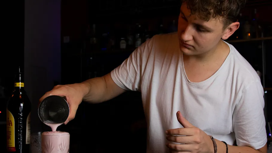 Bartender pouring drink into glass in bar.