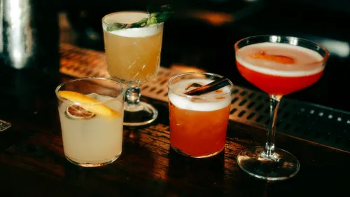 Four colorful cocktails on a wooden bar.