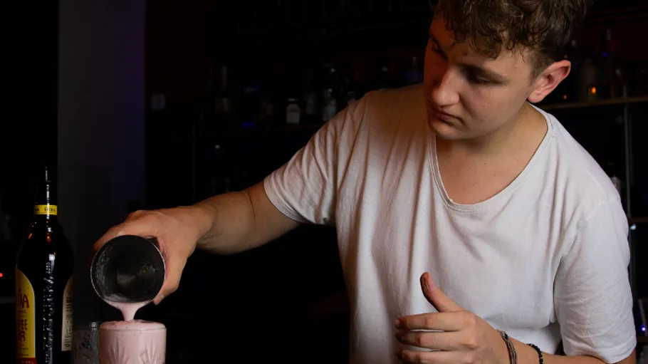 Barmann gießt Getränk in Glas an der Bar.