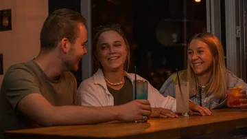 Drei Freunde lachen an einer Bar.