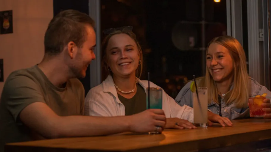 Three friends laughing at a bar.