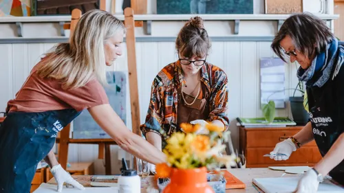 Three women painting together in an art studio.