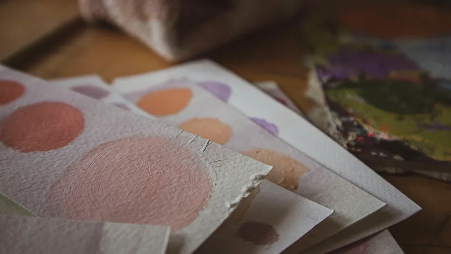 Paint swatches with circles on paper, wooden background.