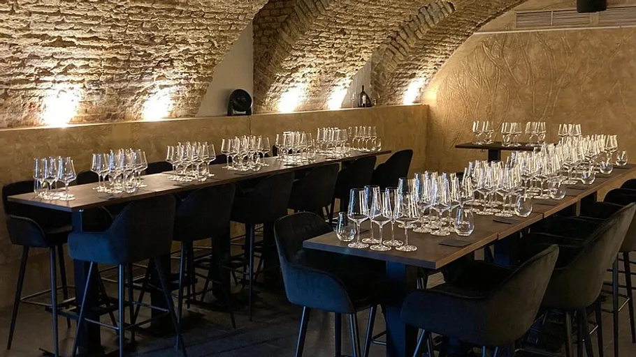 Tables with wine glasses in a brick-walled cellar.