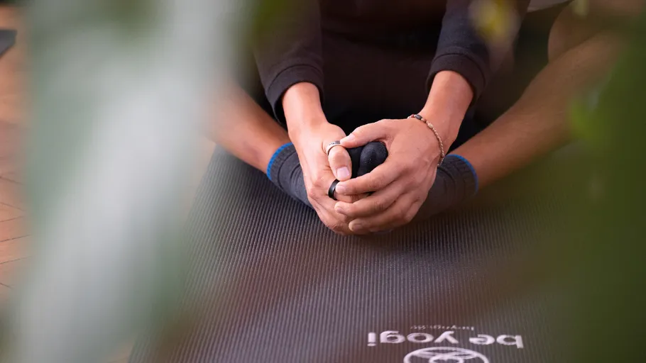 Person dehnt sich auf Yogamatte drinnen.