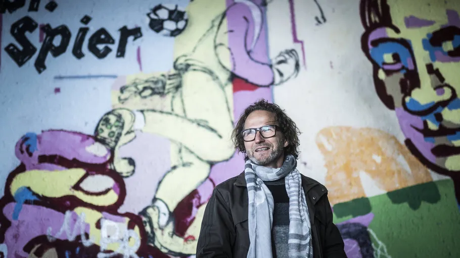 Man standing before colorful graffiti wall.