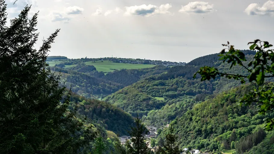 Grüne Hügel und Dorf unter bewölktem Himmel.