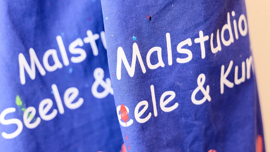 Blue fabric with white text, paint splatters.