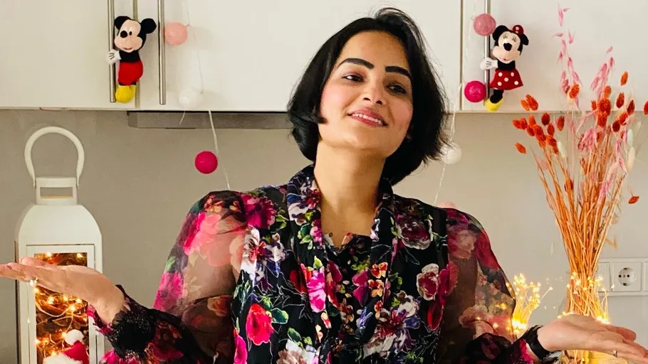 Smiling woman gestures in decorated kitchen.