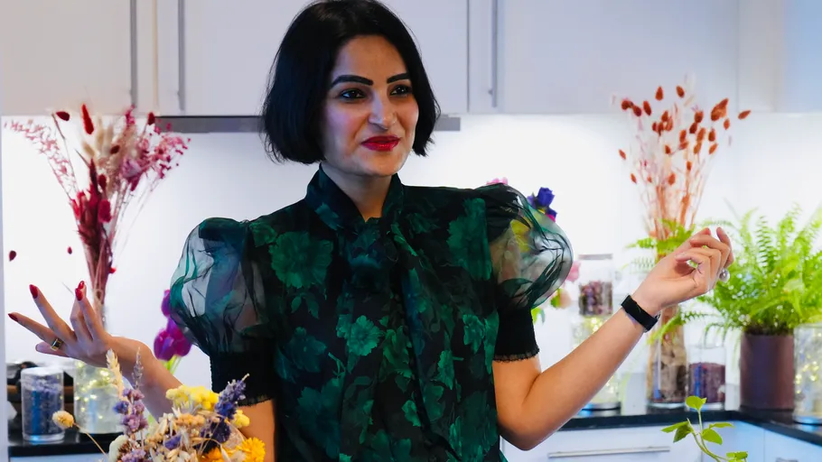 Woman smiling in kitchen, holding flowers.
