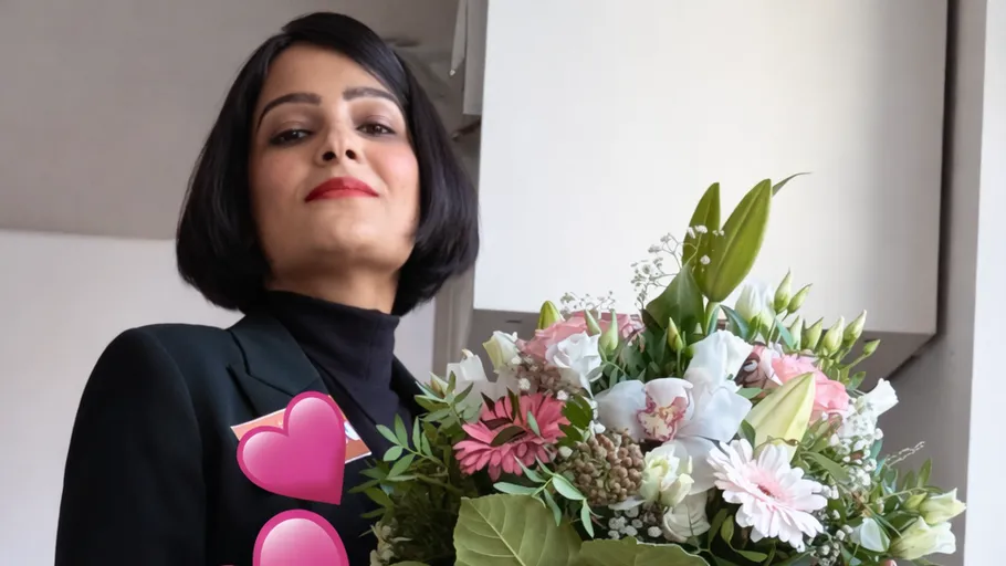 Person holding bouquet indoors, looking confident.