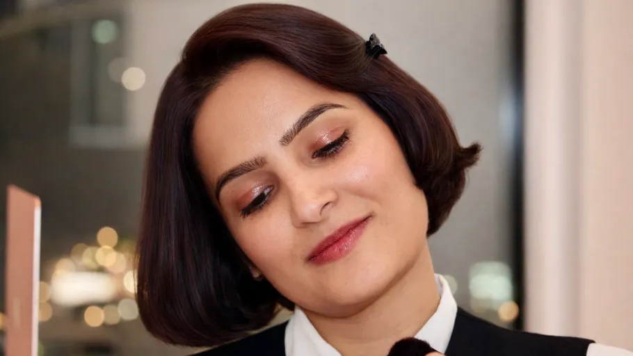 Person trägt Make-up in eleganter Inneneinrichtung auf.