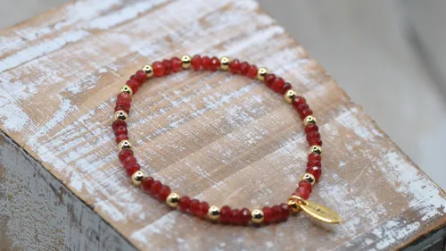 Rotes Perlenarmband auf Holzoberfläche.