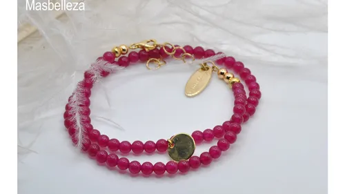 Rosa Perlenarmbänder mit goldenen Anhängern auf Stoff.