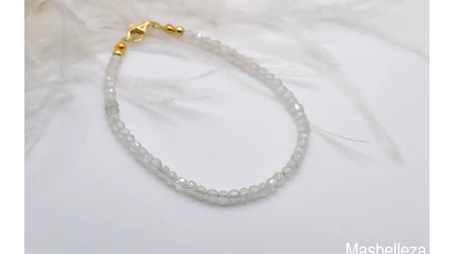 White beaded bracelet on feather background.