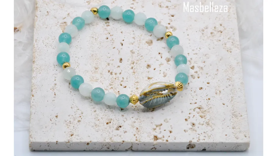 Perlenarmband mit goldenen Akzenten auf Steinoberfläche.