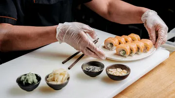 Koch richtet Sushi-Rollen in einer Küche an.