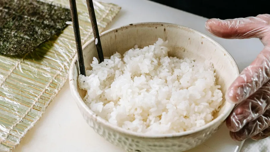 Bowl of rice with chopsticks on table.