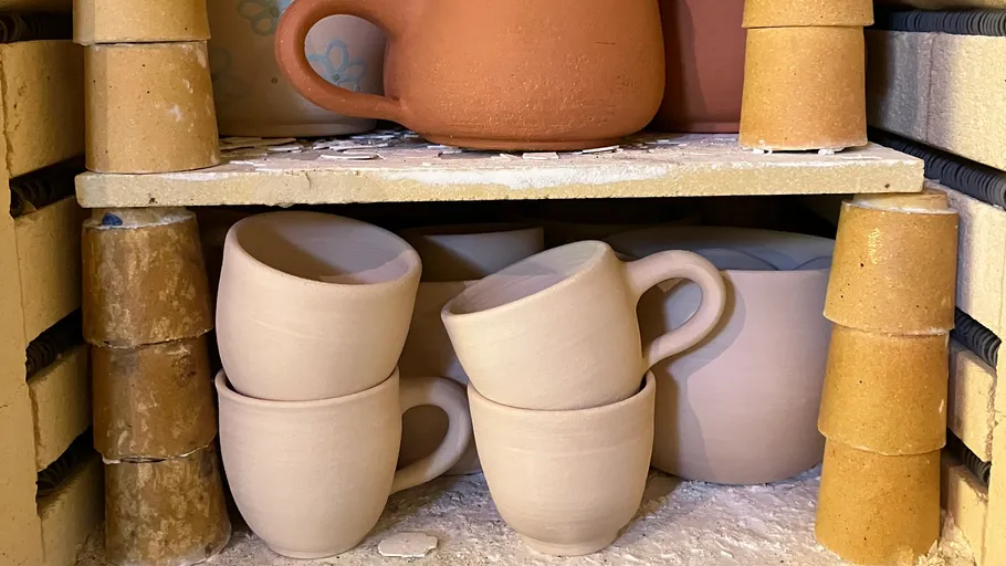 Clay mugs stacked in a pottery kiln.