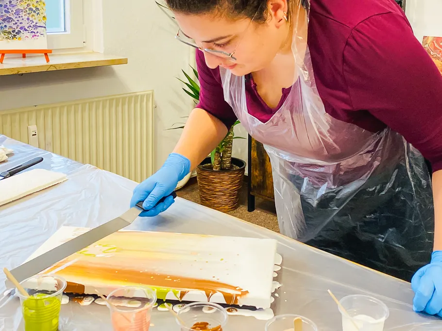 Person spreading paint on canvas in studio.