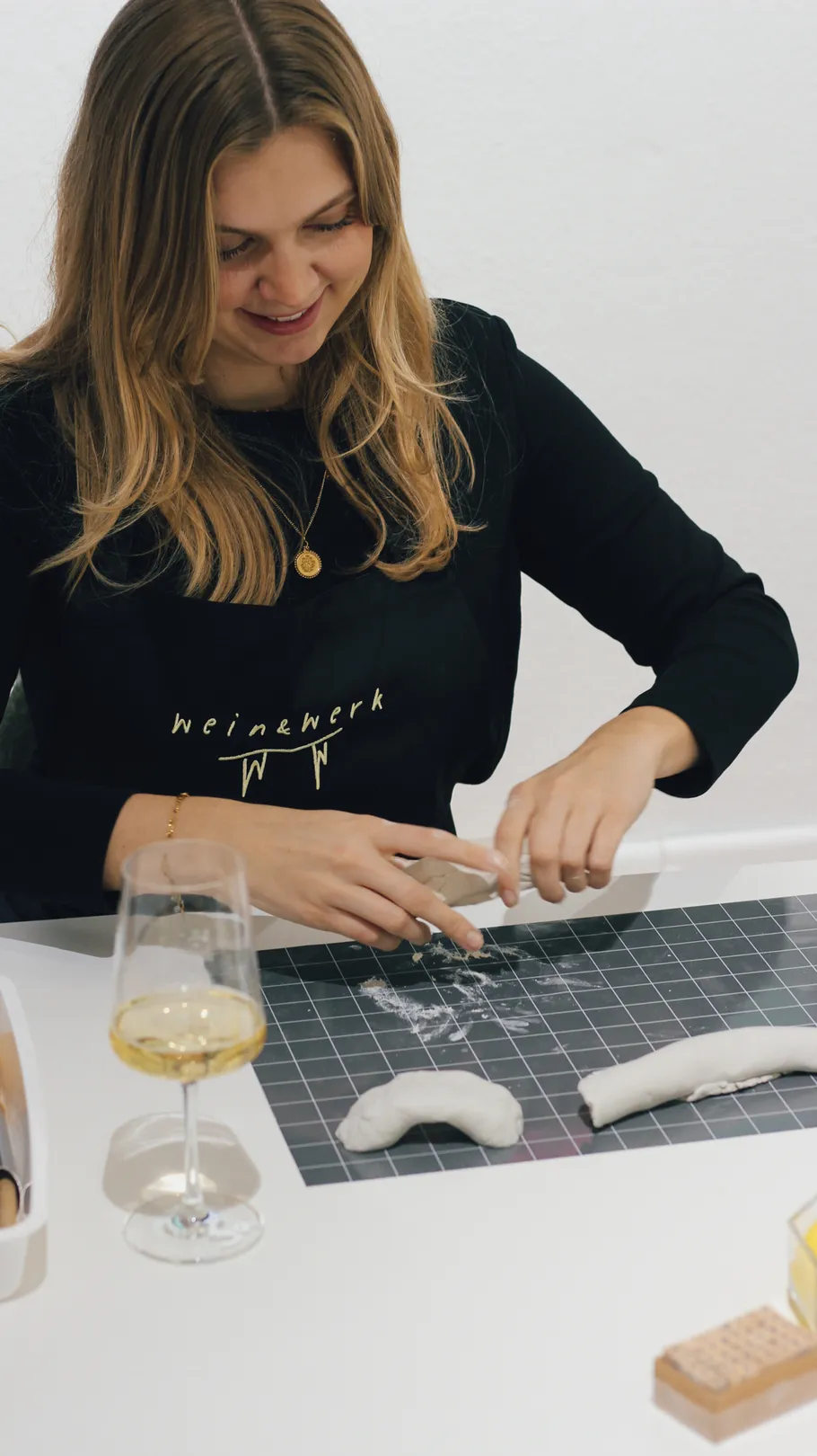 Frau formt Ton auf Tisch, lächelnd.