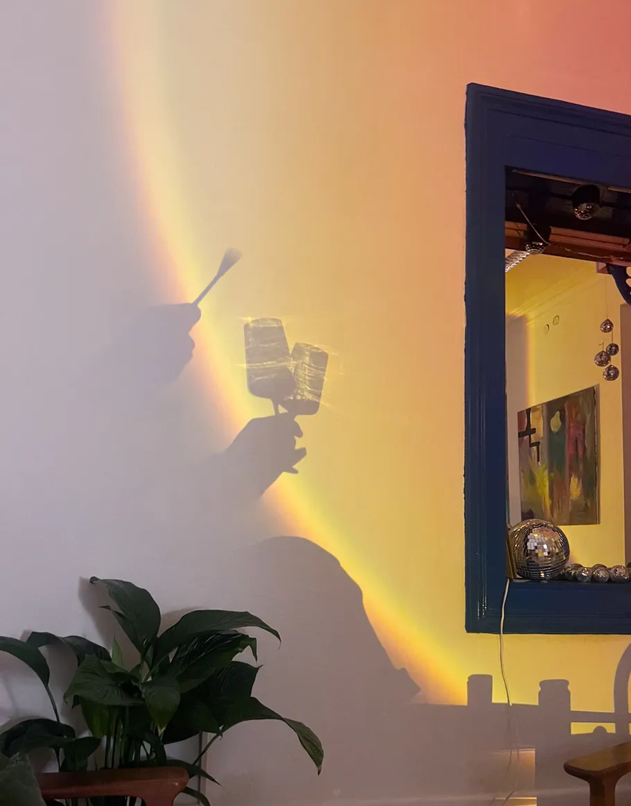 Shadow of hand holding makeup brush on wall.