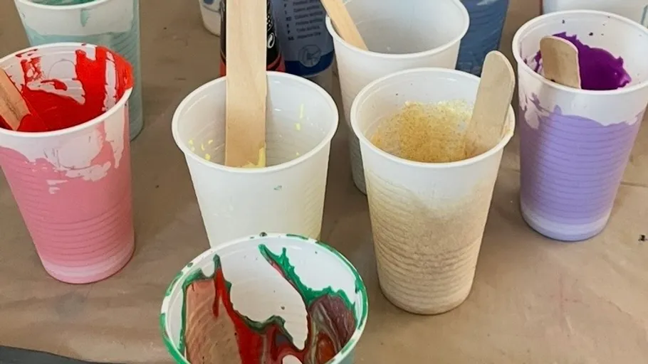 Plastikbecher mit bunter Farbe gefüllt.