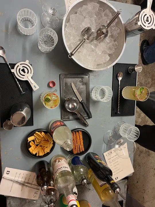 Bartisch mit Getränken und Cocktailzubehör.