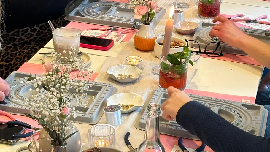 Personen machen Schmuck an einem dekorierten Tisch.