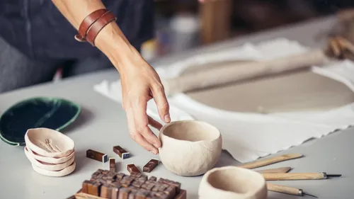 Person crafting pottery at a table.