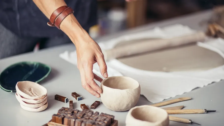 Person crafting pottery at a table.