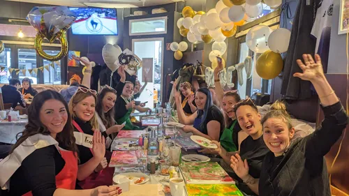 Gruppe lächelnder Frauen an einem festlichen Tisch.