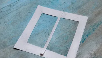 Paper rectangle resting on blue surface.