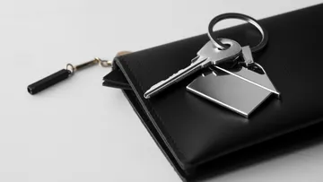 Keys on black wallet, white background.