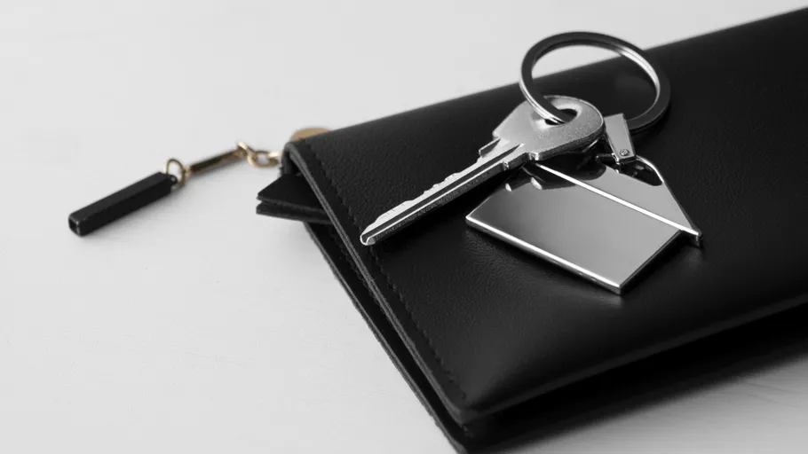 Schlüssel auf schwarzem Portemonnaie, weißer Hintergrund.