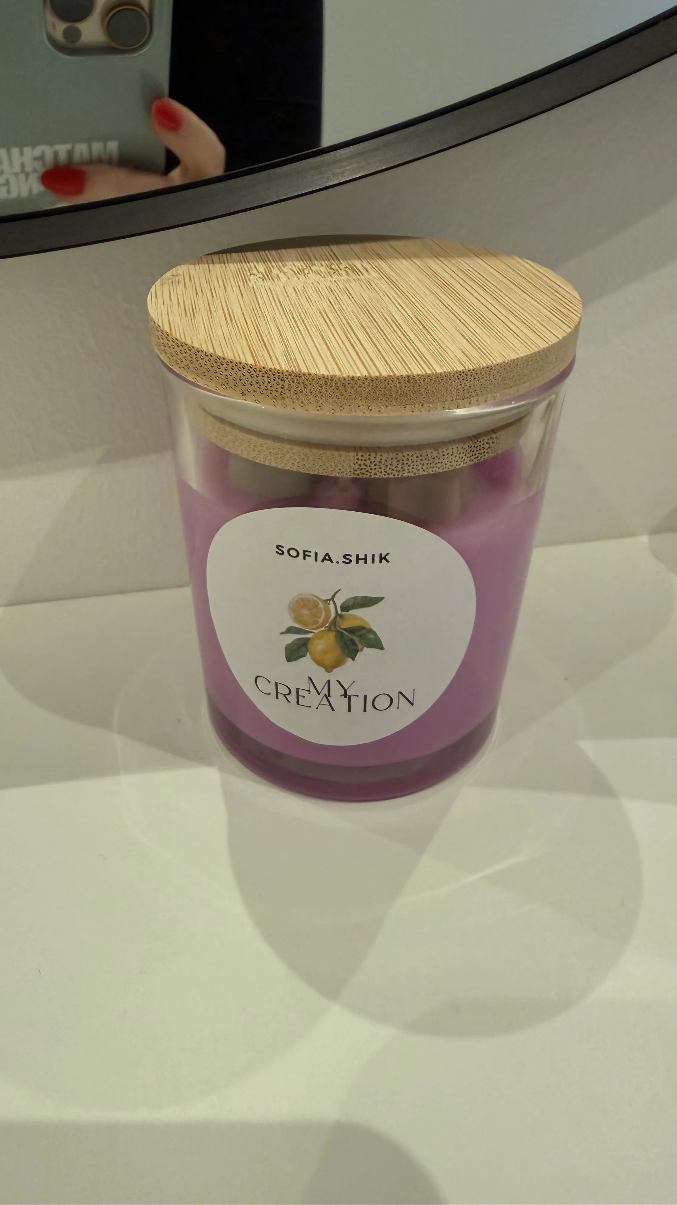 Lila Kerze mit Holzdeckel auf Regal.