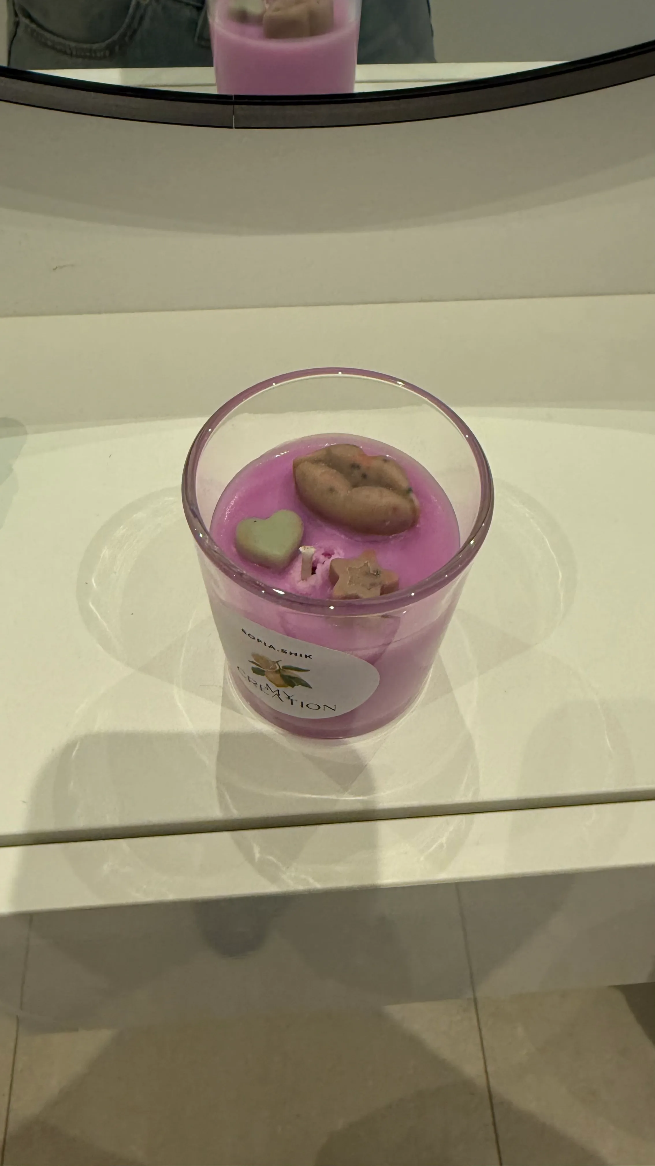 Lila Kerze mit Dekorationen auf einem Regal.